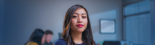 A smiling woman with dark hair and red lipstick, looking directly at the viewer.